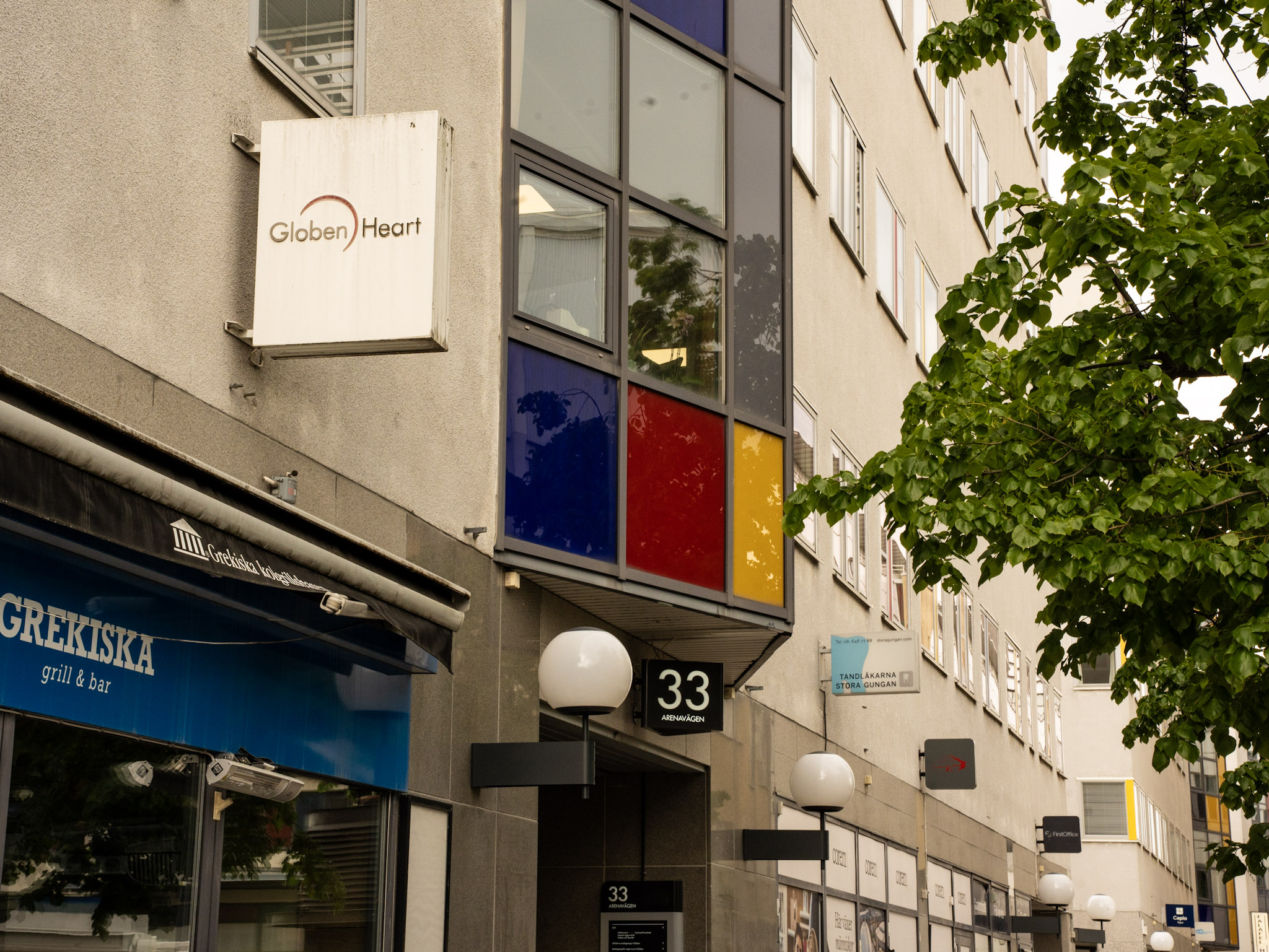 Byggnad med skyltar för Globen Heart, Grekiska grill & bar och adressen Arenavägen 33.